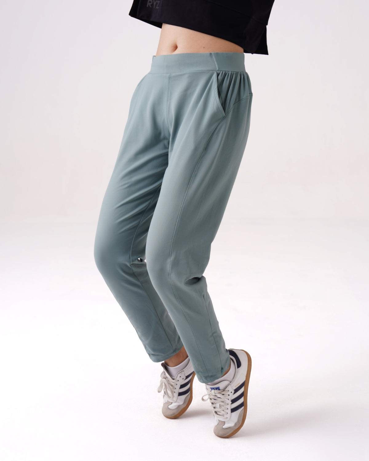 Woman wearing RYZ Enhance All-Day Smart Pants in sage green, styled for both training and everyday wear